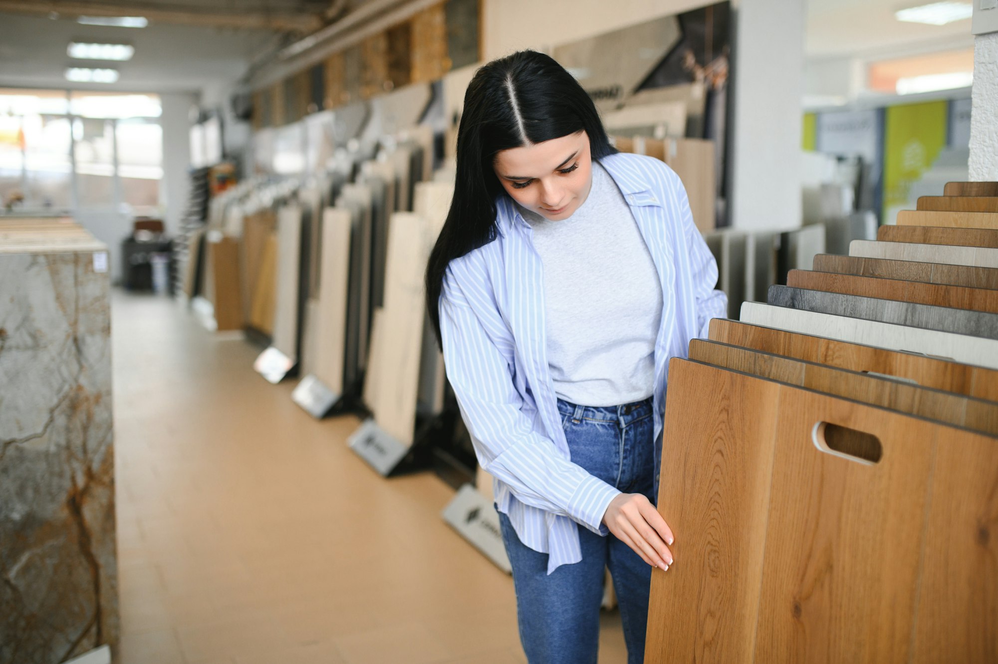 woman choosing laminate floor design from samples in flooring store